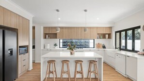 Una cocina moderna con una isla central, armarios de madera y taburetes de bar.