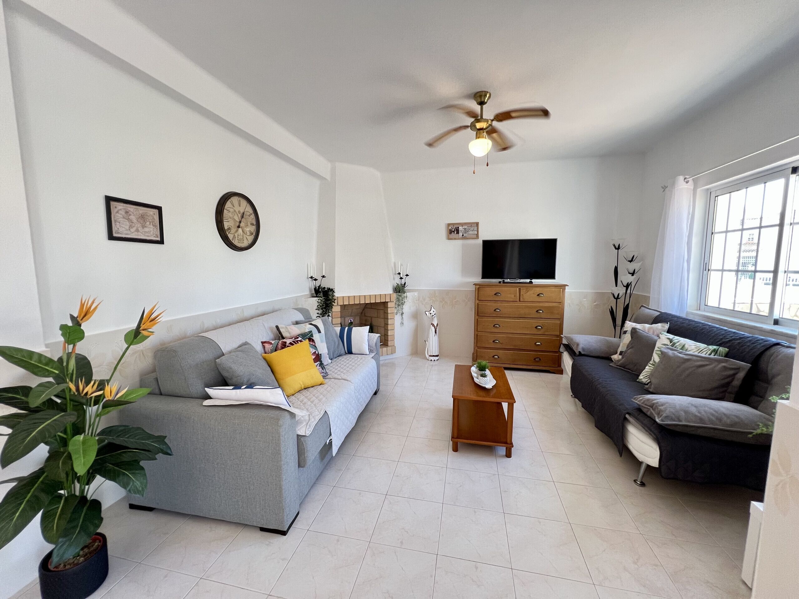 A living room with a grey sofa, a dark sofa, a wooden coffee table, and a ceiling fan.