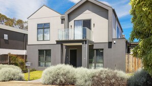 A modern two-story house with a balcony, large windows, and a well-maintained garden. - Inlet Paradise in Rhyll (Rhyll)