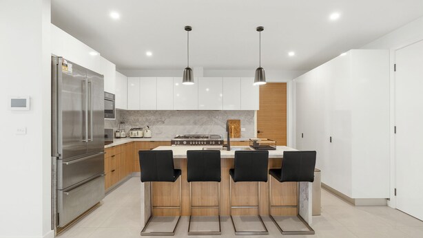 A modern kitchen with a central island, stainless steel appliances, and pendant lighting. - Inlet Paradise in Rhyll (Rhyll)