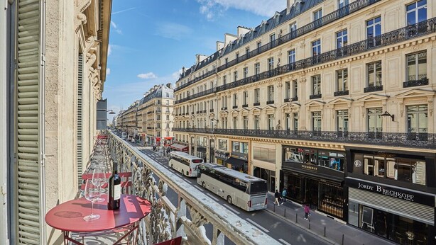A street view with a row of buildings, a bus, and a pedestrian. - 4 Rooms Apartment Opera Vendome (Paris)