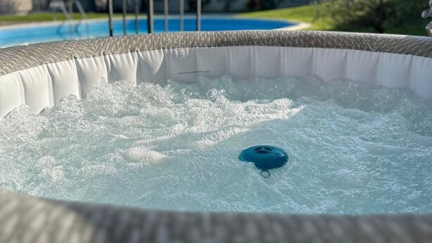 Un bain à remous doté d’un drain bleu, entouré d’une couverture gonflable blanche, le tout installé au bord d’une piscine.