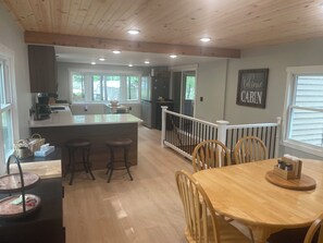 A spacious kitchen with a large island, wooden dining table, and bar stools.