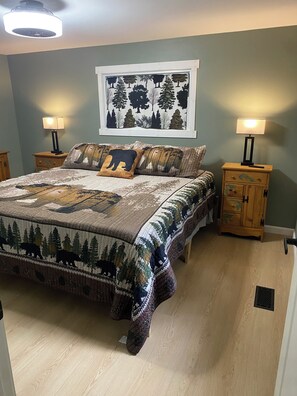 A bedroom with a bed, two nightstands, a framed picture on the wall, and a wooden cabinet.