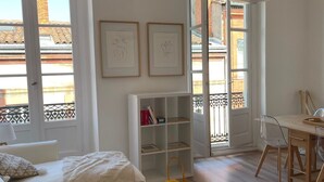 En moderne stue med en hvid sofa, et glasbord og en reol.
