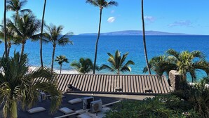 A beachside lounge with palm trees, a wooden deck, and a view of the ocean. - Nestled Between Two Beaches Kihei Oceanview 2BR Condo Panoramic Views Pool (Kihei)