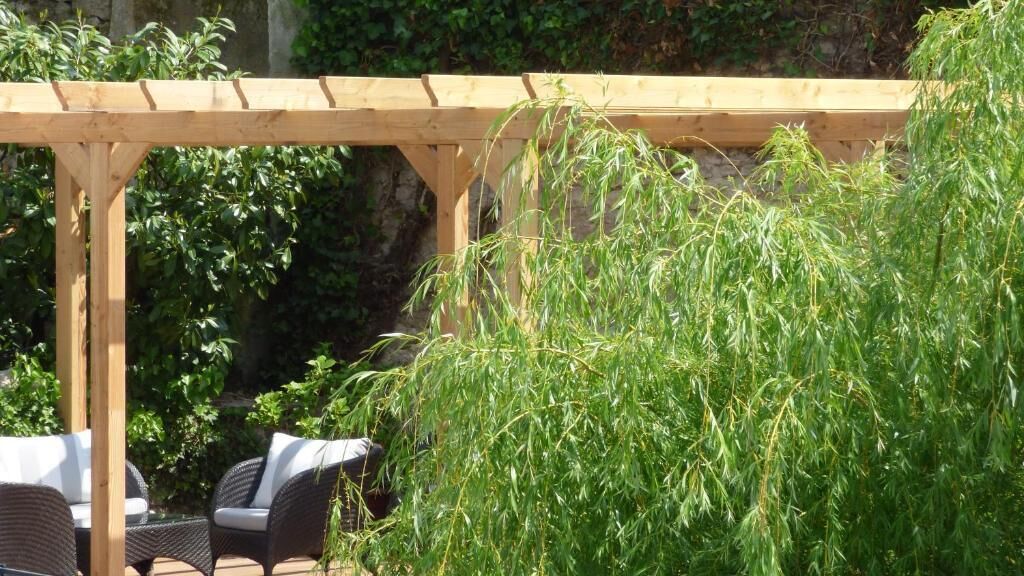 A wooden pergola structure with a seating area underneath.