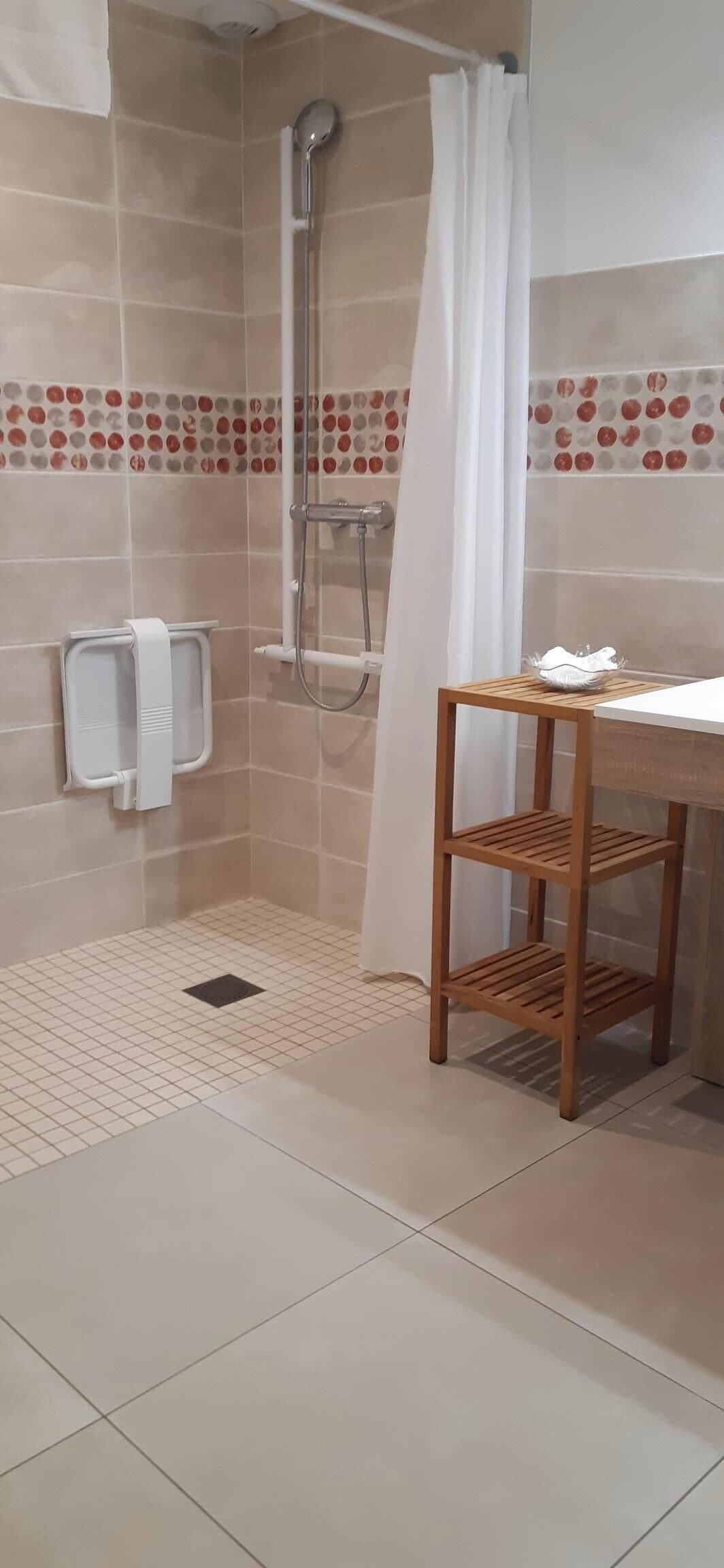 Un baño con ducha, lavamanos y estante de madera.