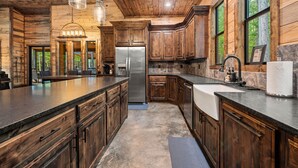 A spacious kitchen with wooden cabinets, a large island, stainless steel appliances, and pendant lighting.