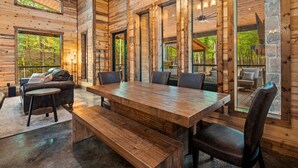 A wooden interior with a large dining table, multiple chairs, and a sofa.