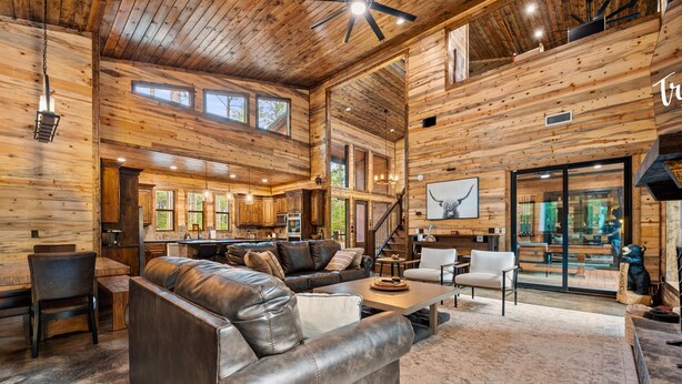 A spacious living area with a leather sofa, a dining table, and a kitchen in the background.