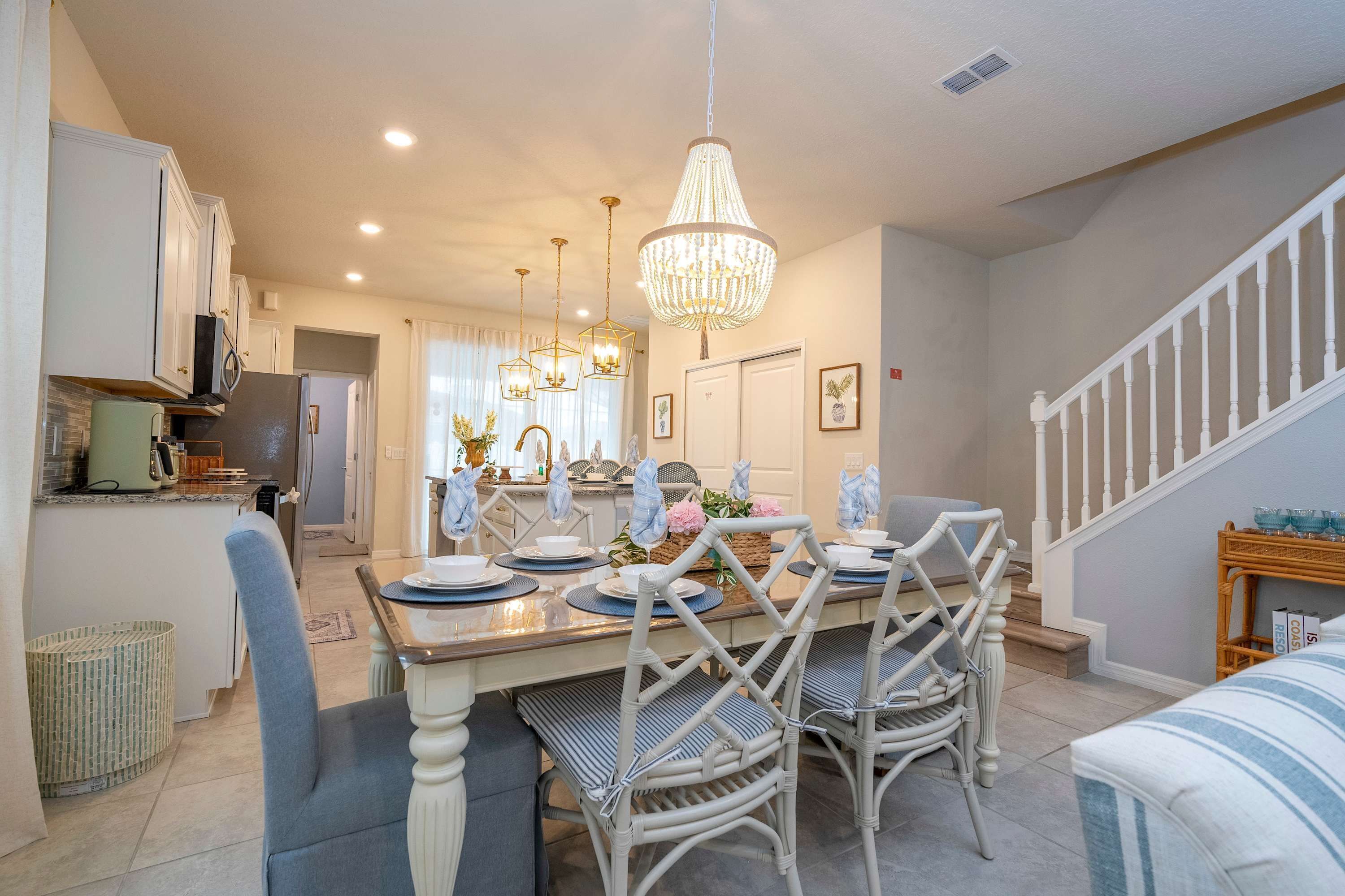 A dining area with a wooden table set for four, surrounded by wicker chairs.