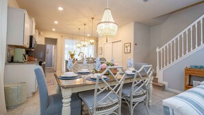 A dining area with a wooden table set for four, surrounded by wicker chairs. - Amazing 5 Suite Home With Resort-style Amenities (Davenport)