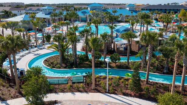 A resort with a large pool area, multiple lounge chairs, and palm trees. - Amazing 5 Suite Home With Resort-style Amenities (Davenport)