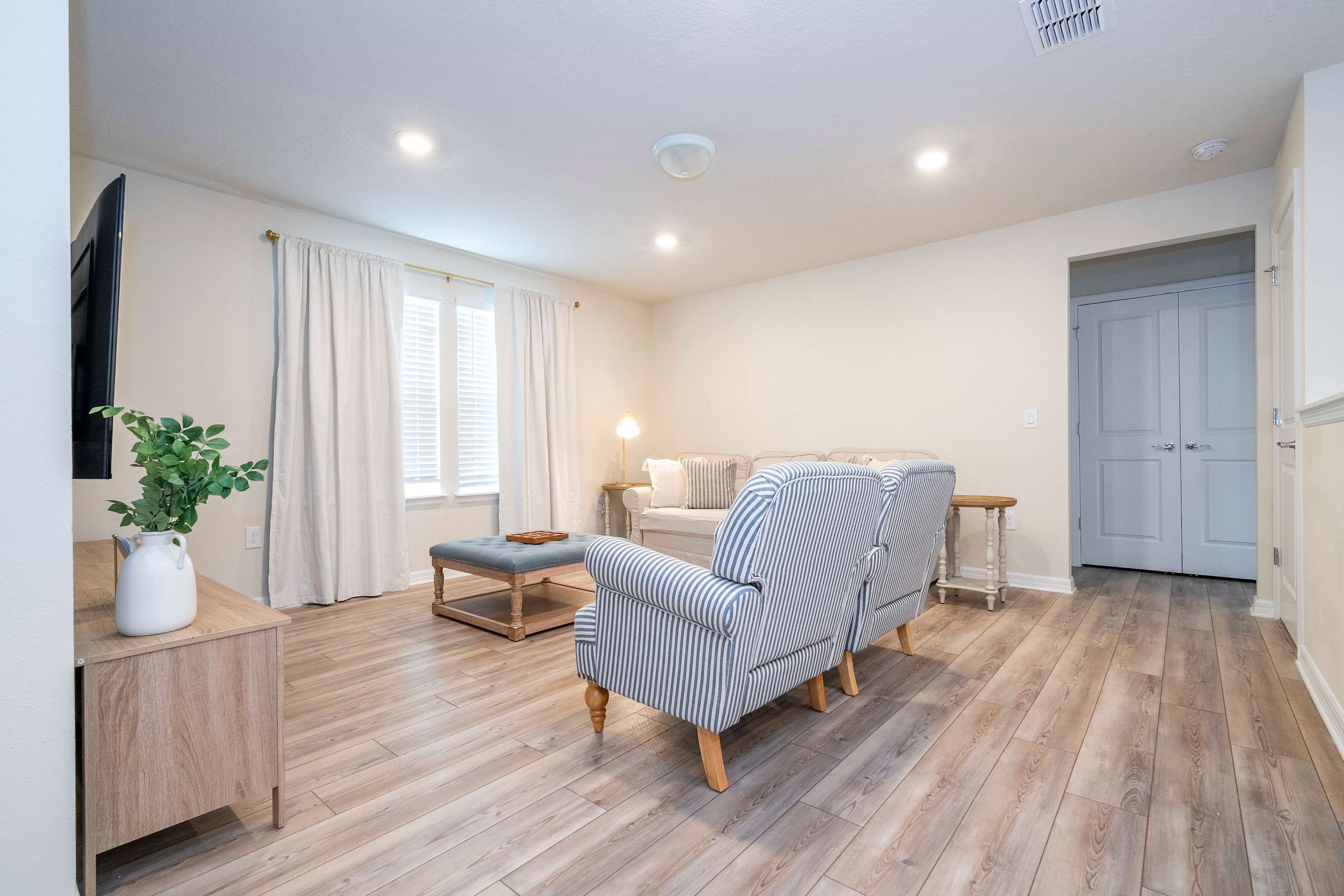 A spacious living room with a striped sofa, a wooden coffee table, and a small side table.