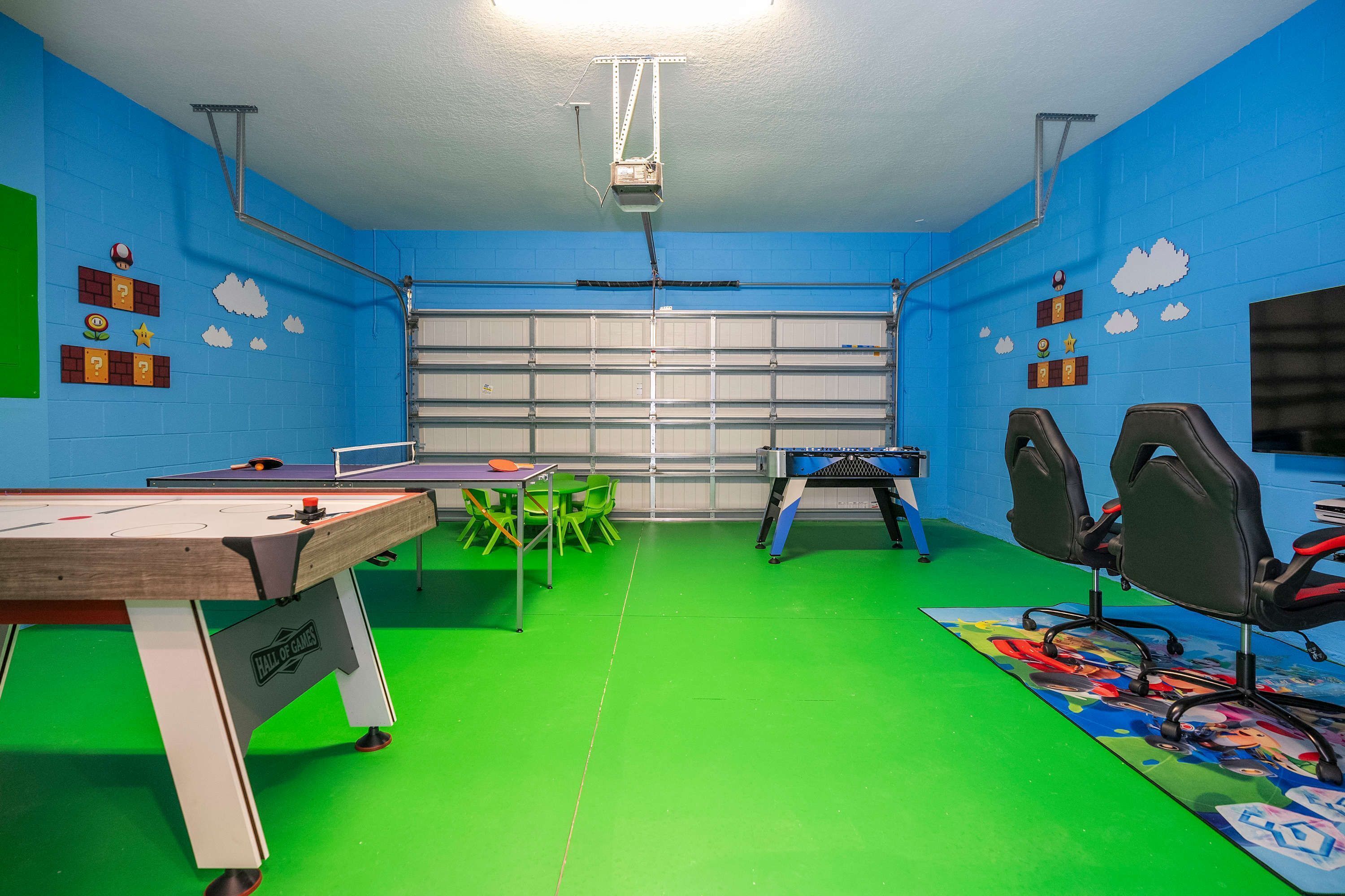Una stanza con tavolo da biliardo, sedie verdi e tavolo per ping pong.