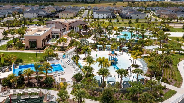 A residential area with a large swimming pool, palm trees, and houses. - Beautiful 5 Bed Home in Solara With Private Pool (Kissimmee)