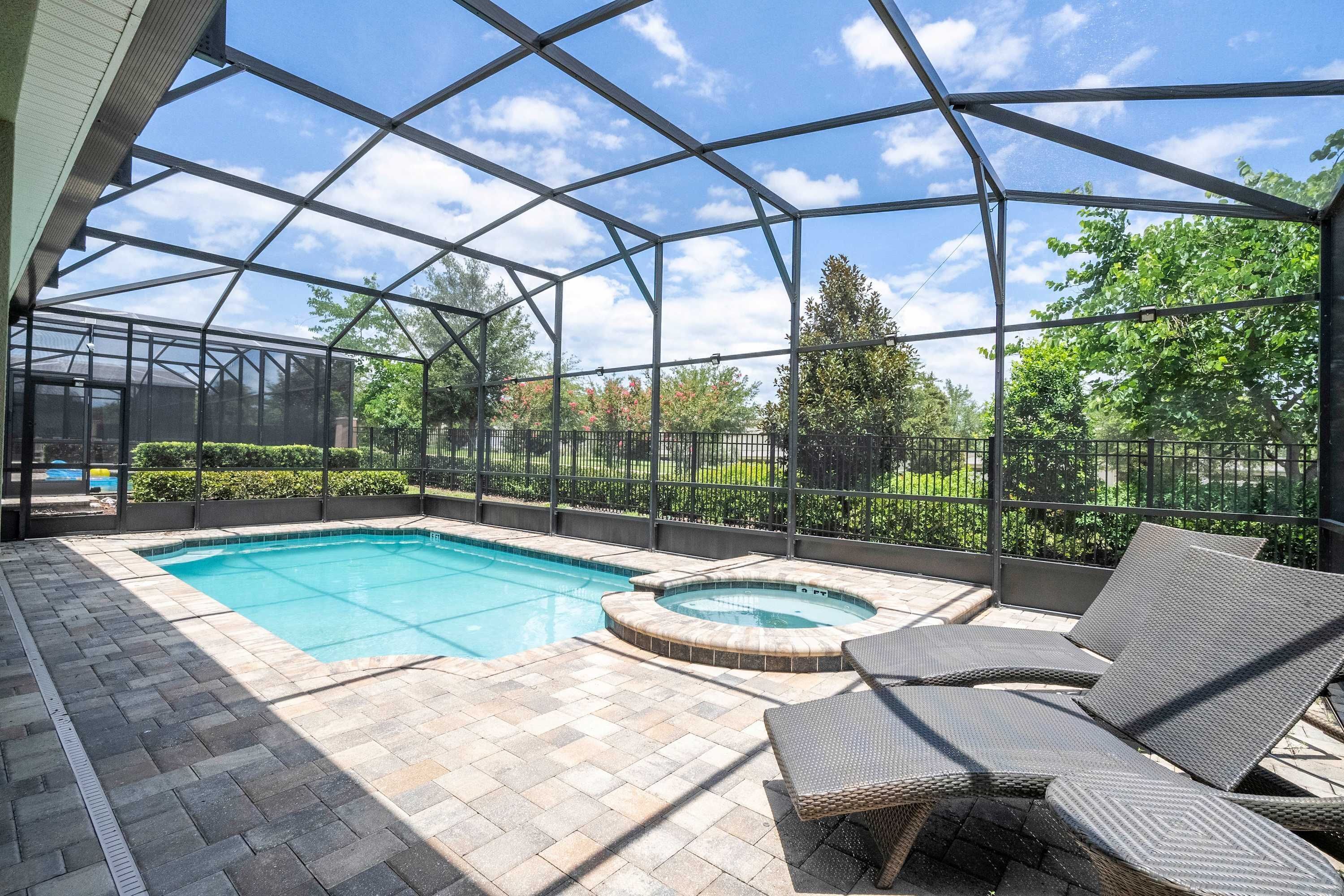 Una piscina exterior techada con sillones de descanso y un jacuzzi.