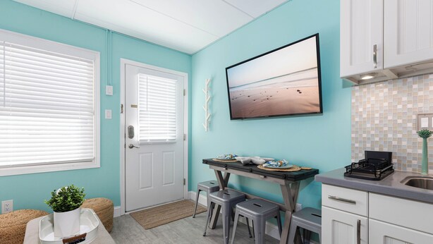 A kitchen with a teal wall, white cabinets, a countertop, and a window with blinds. - Cozy 1BR condo North Wildwood with WiFi, AC, 1.5 blk to beach, Boardwalk, Moreys (North Wildwood)
