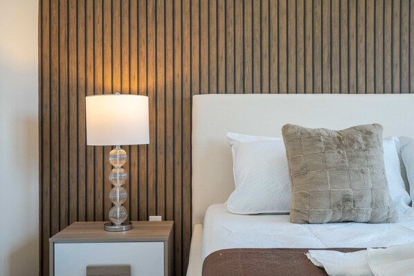 A neatly made bed with two pillows, a bedside lamp, and a wooden panel wall.