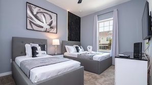 Ein modernes Hotelzimmer mit zwei Betten, einem Schreibtisch und einem großen Fenster.