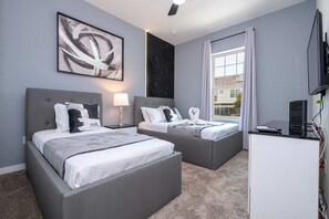 Ein modernes Hotelzimmer mit zwei Betten, einem Schreibtisch und einem großen Fenster.