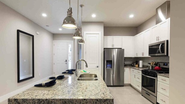 A modern kitchen with granite countertops, stainless steel appliances, and pendant lighting. - Stylish 4bed Townhome at Summerville Near Disney (Kissimmee)