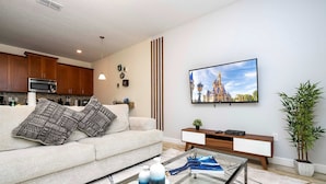 A modern living room with a sofa, coffee table, and a flat-screen TV mounted on the wall. - Great Home Mickey Harry Potter Beds Top Spot (Kissimmee)