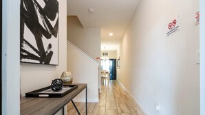 A hallway with a wooden bench, a black abstract painting, and a 'No Smoking' sign. - Great Home Mickey Harry Potter Beds Top Spot (Kissimmee)