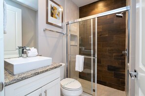 Une salle de bain moderne avec une douche à parois de verre, un lavabo blanc et des toilettes.