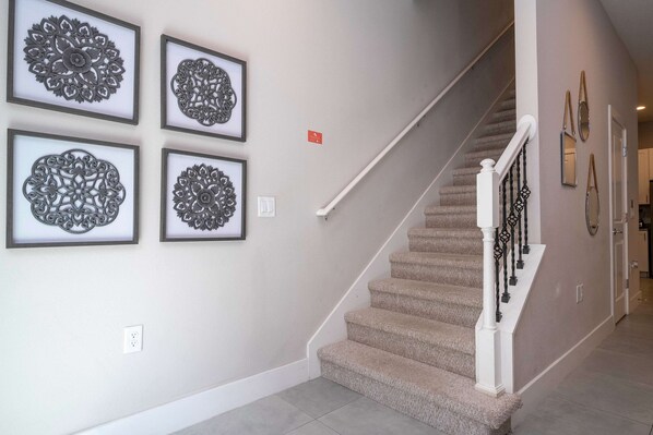 A staircase with a white handrail and beige carpeted steps. - Modern Chic Home Mickey and Toy Story Rooms (Kissimmee)