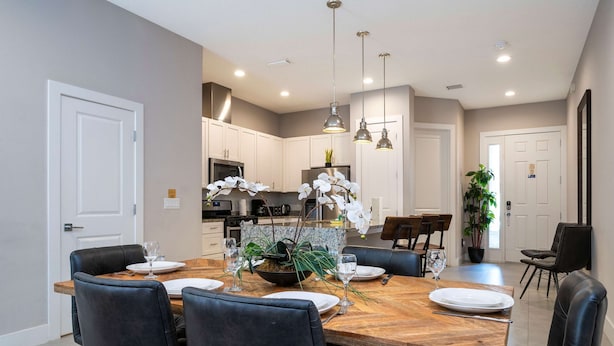 A modern dining area with a wooden table, black chairs, and pendant lighting. - Modern Chic Home Mickey and Toy Story Rooms (Kissimmee)