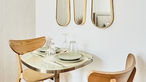 A dining area with a round table, two wooden chairs, and three wall-mounted mirrors. - Chic Studio AC - Center of Paris-bourse (Paris)