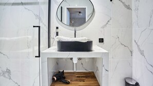 A bathroom with a white marble sink, a round mirror, and a towel rack. - Chic Studio AC - Center of Paris-bourse (Paris)
