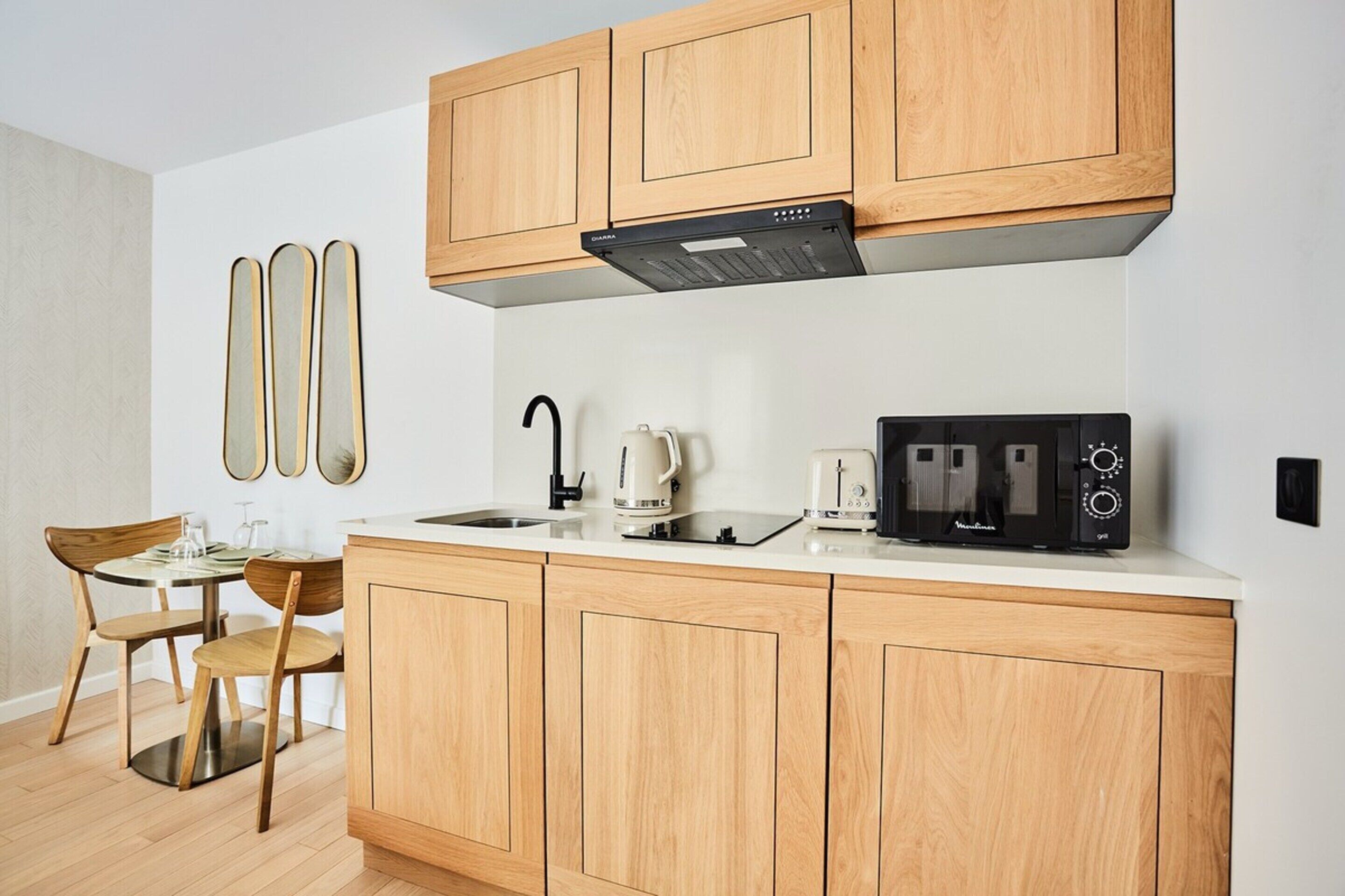 A modern kitchen with wooden cabinets, a built-in oven, a coffee maker, and a toaster.