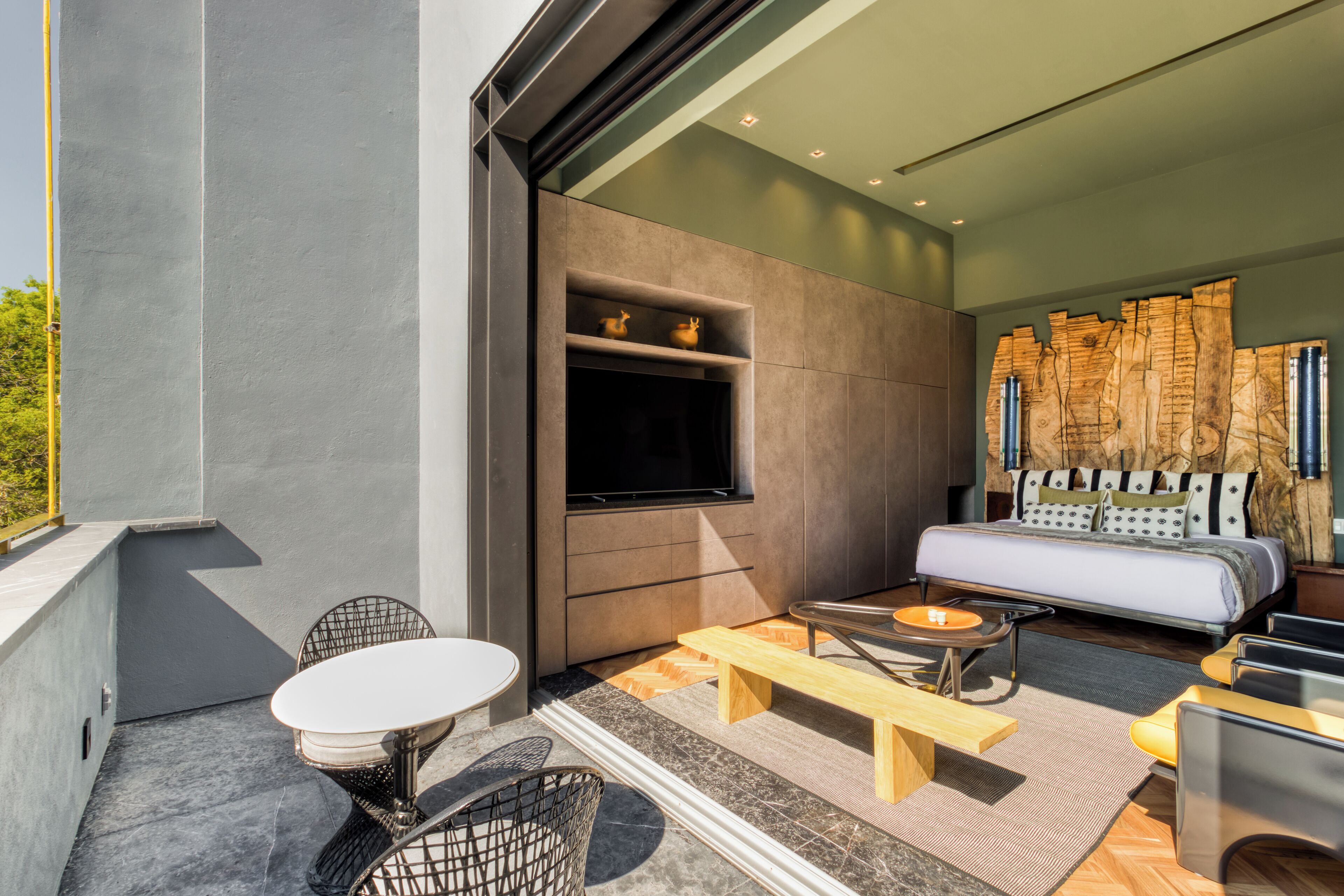 Une chambre moderne avec un grand lit, une télévision et un coin salon comprenant une table et des chaises.