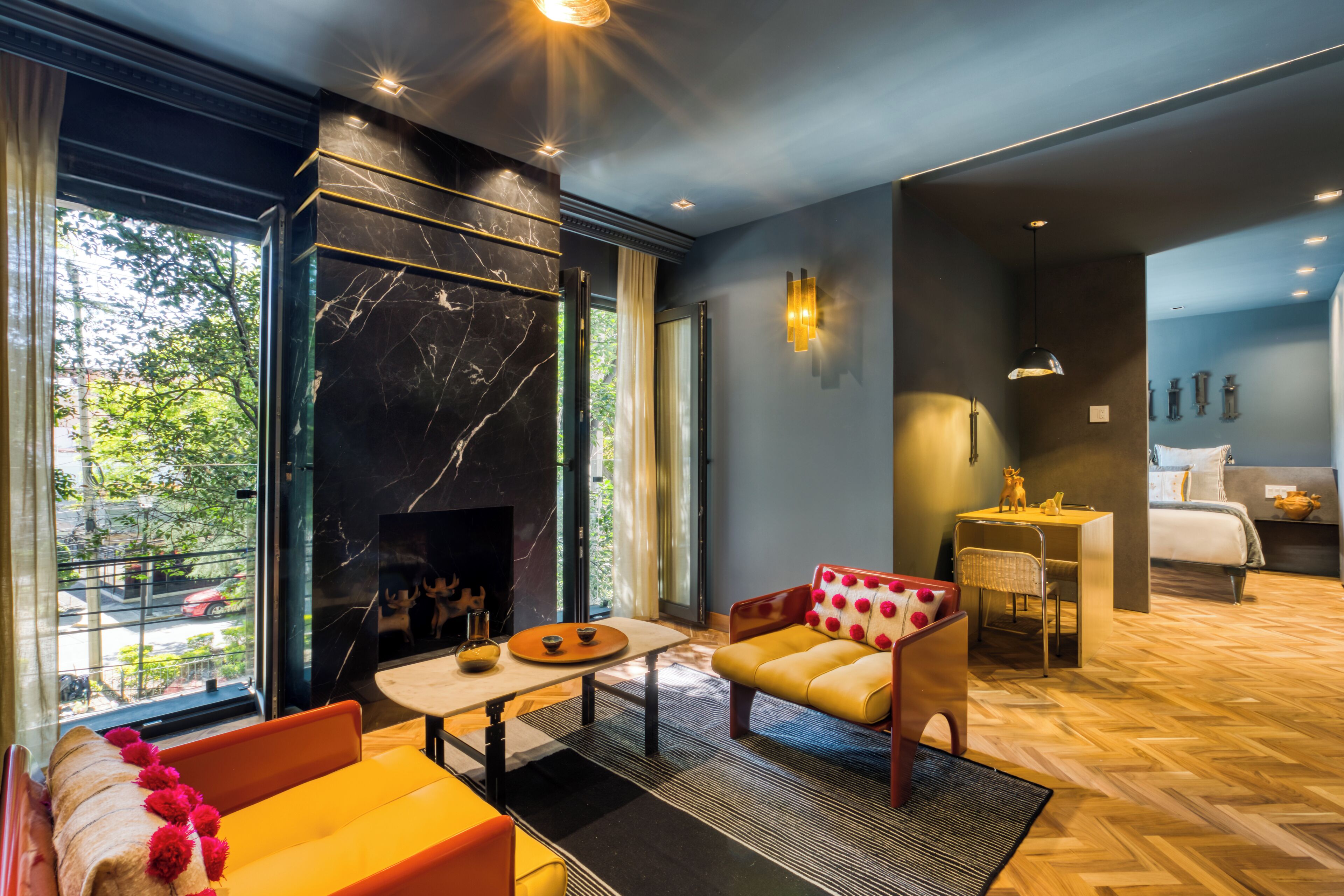Een moderne hotelkamer met een open haard, een bank, een eettafel en uitzicht op het omliggende landschap.