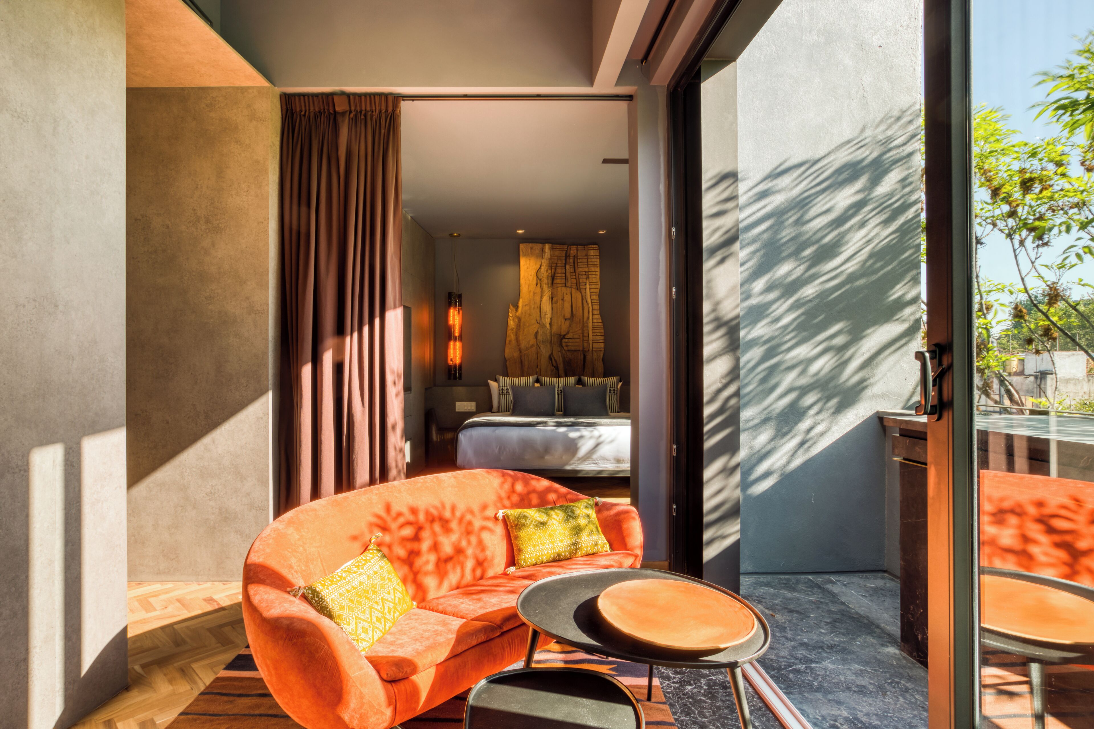 A modern hotel room with a large window, a sofa, a small table, and a bed.