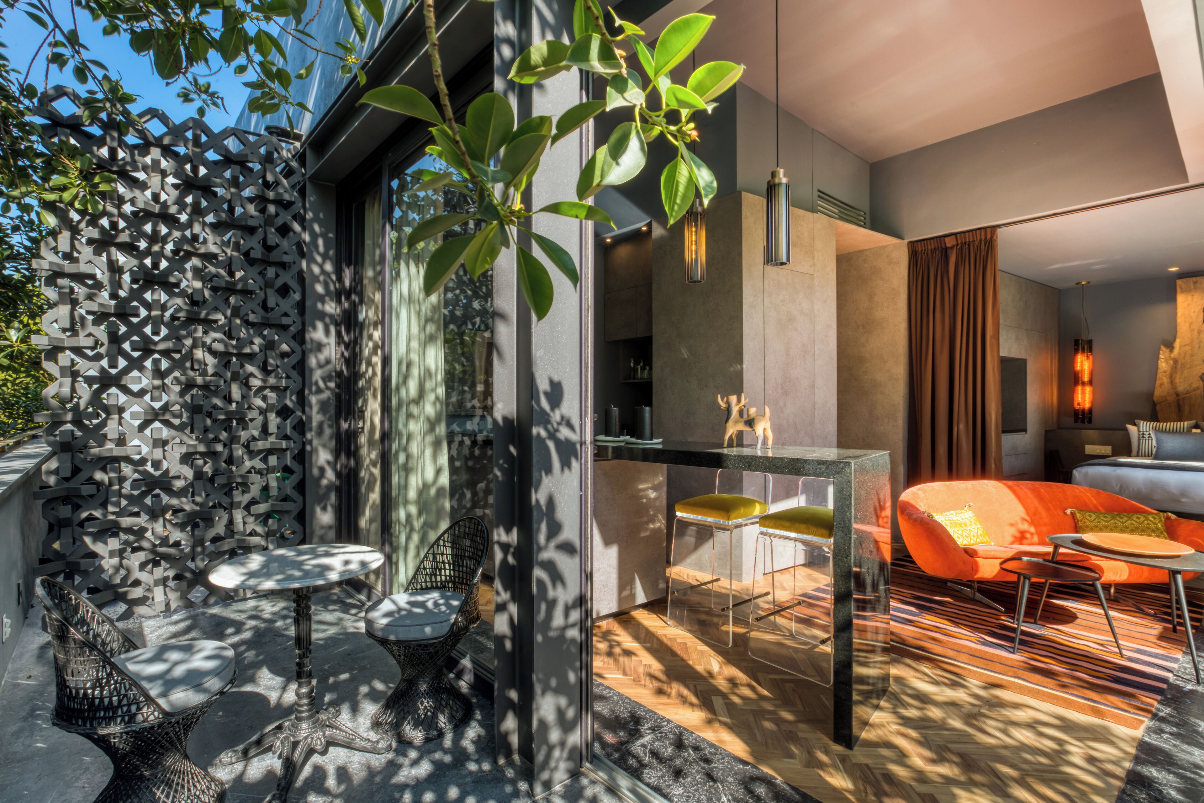 A modern interior with a dining area, a sofa, and a view of the outdoors.