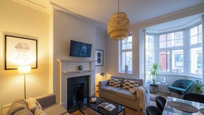 Una sala de estar moderna con chimenea, sofá, mesa de centro y televisor.