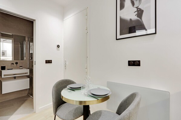 Un espace repas moderne avec une table ronde, deux chaises grises et un design minimaliste.