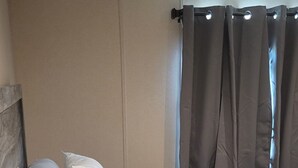A bed with a wooden headboard, white bedding, and a curtain with a light fixture. - Your Peaceful Georgetown Escape (Georgetown)