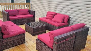 A patio with wicker furniture and red cushions.