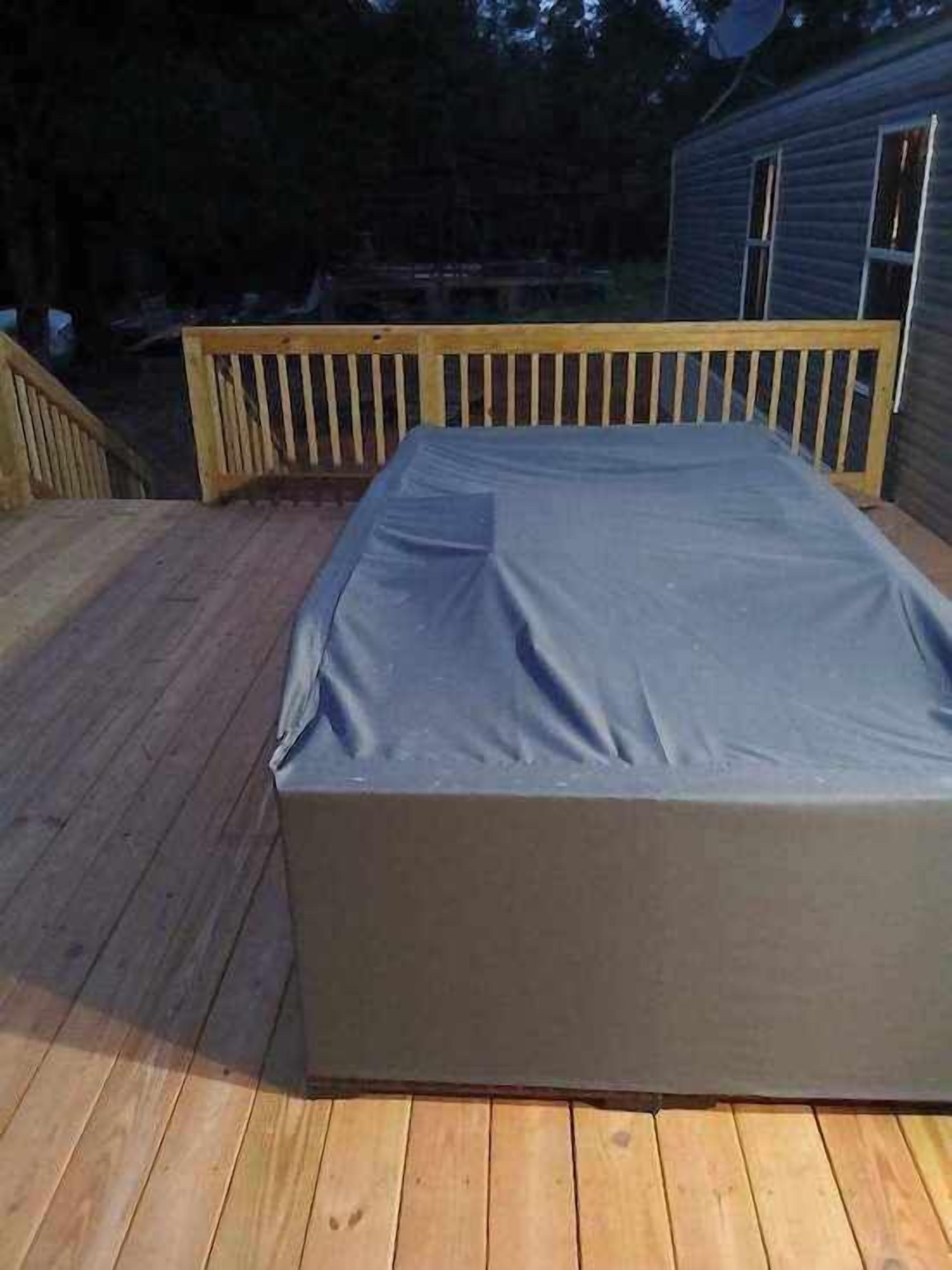 Una terraza techada al aire libre con barandal de madera y una lona azul que cubre una zona rectangular.