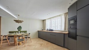 A modern kitchen with a herringbone wood floor, a dining area with a wooden table and chairs, and a large window with sheer curtains. - Spacious AC Flat Luxembourg St Germain des Pres (Paris)