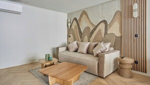 A modern living room with a beige sofa, a wooden coffee table, and a textured wall. - Spacious AC Flat Luxembourg St Germain des Pres (Paris)