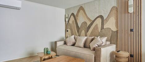 A modern living room with a beige sofa, a wooden coffee table, and a textured wall.