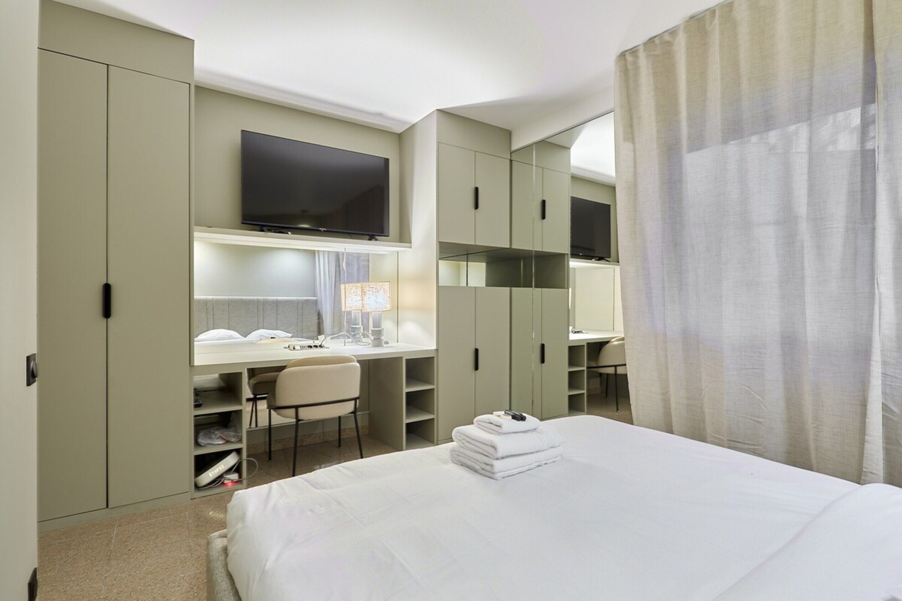 Een hotelkamer met een bed, een bureau, een stoel, een televisie en een kledingkast.