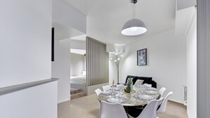 A modern dining area with a marble table, white chairs, and a pendant light. - Modern Parisian Apartment Center of Paris (Paris)