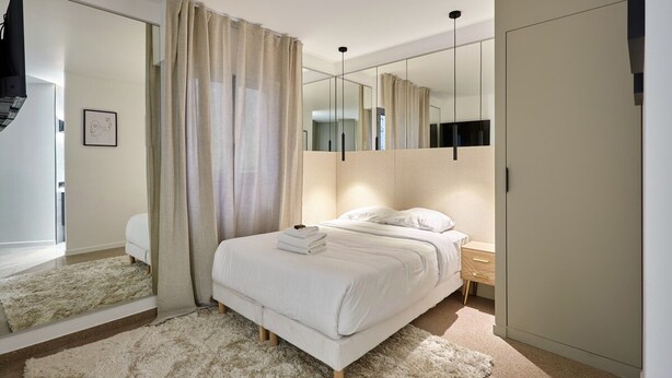 A bedroom with a bed, a wardrobe, a mirror, and a door. - Modern Parisian Apartment Center of Paris (Paris)